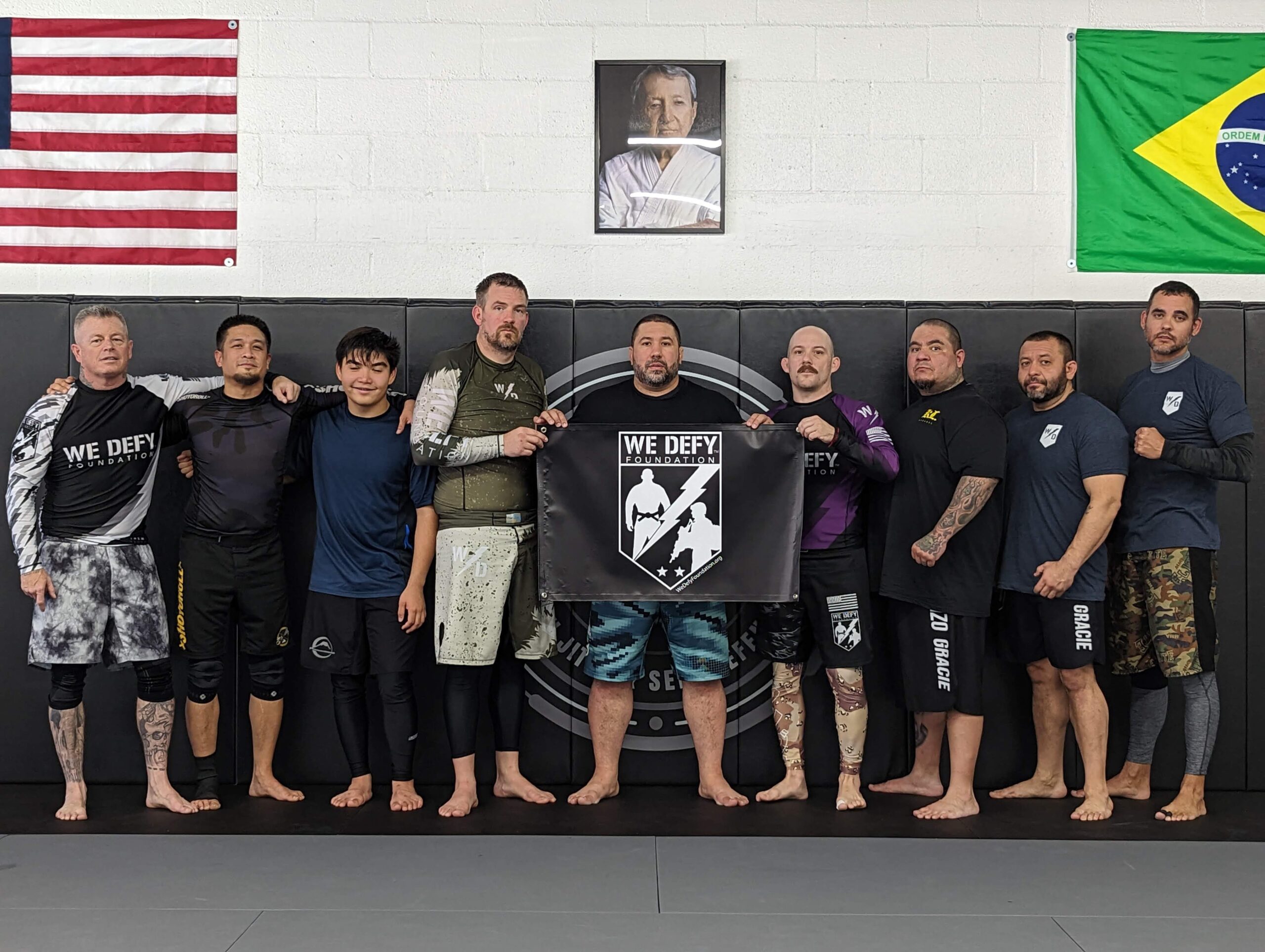 The Unlimited Jiu Jitsu team poses for a photo at the annual We Defy Foundation Ruck Roll, 2022 holding the We Defy Foundation banner.